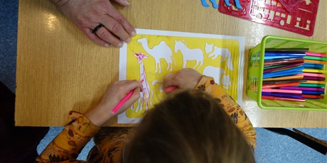 Powiększ grafikę: Dziewczynka rysuje zwierzęta za pomocą szablonu.