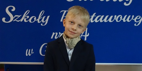 Powiększ grafikę: Chłopiec elegancko ubrany stoi przed tablicą z napisem: 23 lutego dzień otwarty Szkoły Podstawowej nr 44 w Gdańsku.