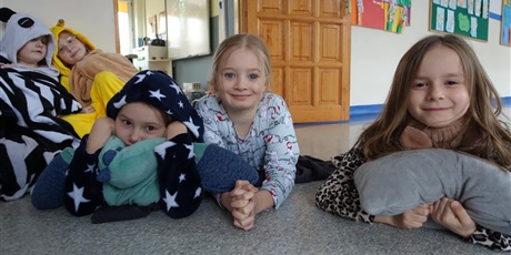 Powiększ grafikę: Trzy dziewczynki w piżamach - lezą na podłodze przytulone do poduszek i maskotek.