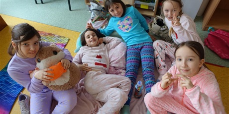 Powiększ grafikę: Grupa dziewczynek ubranych w piżamy - leżą na kocach.