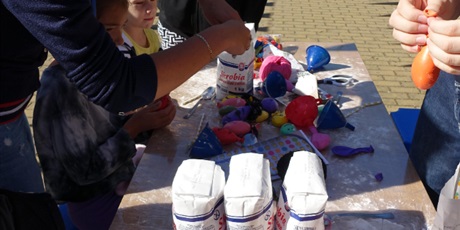 Powiększ grafikę: Uczniowie robią gniotki z balonów i mąki ziemniaczanej.