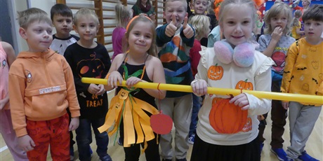 Powiększ grafikę: Uśmiechnięte dzieci w przebraniach nawiązujących do dyni. Na pierwszym planie dwie dziewczynki trzymające plastikową rurkę.