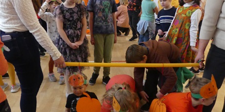 Powiększ grafikę: Dwie osoby trzymają plastikową rurkę, dzieci przechodzą pod nią.