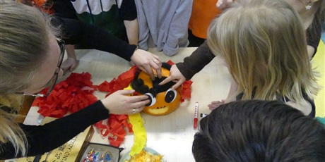 Powiększ grafikę: Dzieci ozdabiają dynię - przyklejają oczy, włosy.