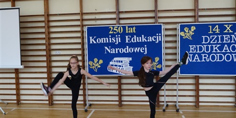 Powiększ grafikę: Dwie dziewczynki występują - prezentują figury gimnastyczne.