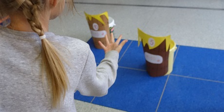 Powiększ grafikę: Dziewczynka rzuca piłką do celu - baryłki miodu z napisem 5.