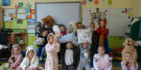 Powiększ grafikę: Grupa dzieci - ubrane w piżamy, mają w dłoniach poduszki i maskotki.