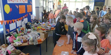 Powiększ grafikę: Stoisko z loterią - przed nim duża grupa dzieci.