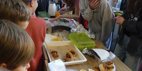 Powiększ grafikę: Stoisko ze słodkościami. Starsza dziewczyna obsługuje, pochyla się i słucha, co mówi do niej dziecko.