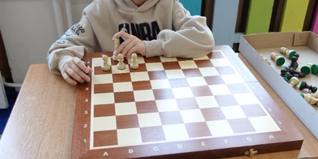Powiększ grafikę: Chłopiec siedzi przed szachownicą. Widać napis: Szachy z Antkiem.