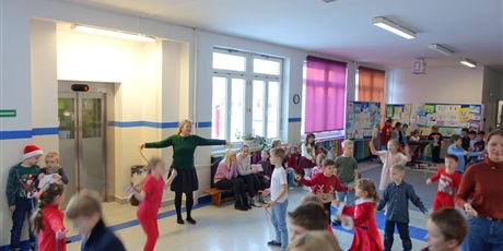 Powiększ grafikę: Nauczycielka stoi na korytarzu ze skakanką w dłoni - przed nią grupa dzieci ze skakankami.