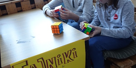 Powiększ grafikę: Dwóch chłopców siedzi przy stole, układają kostki Rubika.