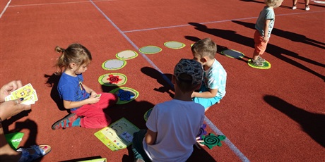 Powiększ grafikę: Dzieci siedzą na boisku, grają w duże Pędzące żółwie.