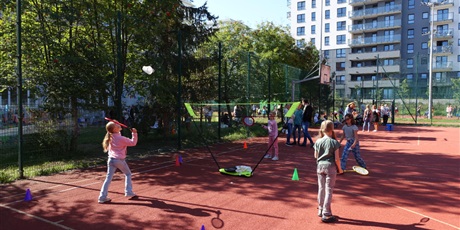 Powiększ grafikę: Boisko szkolne - dzieci bawią się, grają w badmintona.