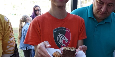 Powiększ grafikę: Uśmiechnięty chłopiec pokazuje talerz z ciastami.