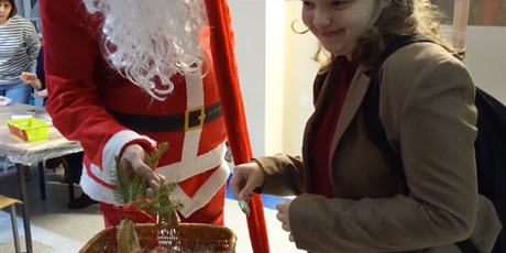 Powiększ grafikę: Dziewczyna wyciąga cukierek z kosza od św. Mikołaja.
