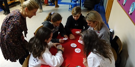 Powiększ grafikę: Grupa uczniów i nauczycielki, grają w grę Dobble.