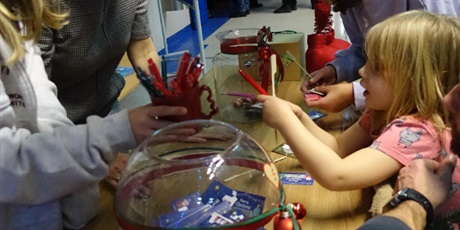 Powiększ grafikę: Dziewczynka wybiera z kubka długopis - nagrodę. Obok niech szklana kula z losami.