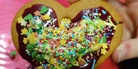 Powiększ grafikę: Piernikowe serce ozdobione czekoladą i kolorowymi posypkami.