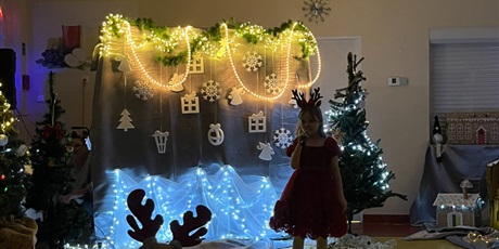 Powiększ grafikę: Dziewczynka stoi na środku sali, śpiewa do mikrofonu. W sali jest zgaszone światło, w tle widać dekoracje, światełka.