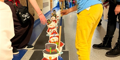 Powiększ grafikę: Dziecko trzyma w dłoni kij, uderza piłkę, która musi trafić w dziurę w stojących tekturowych bałwanach.