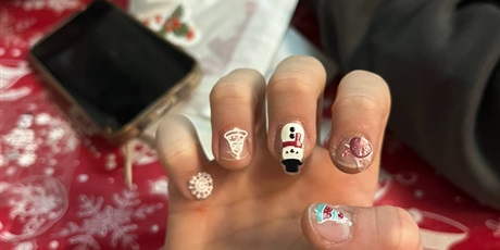 Powiększ grafikę: Widać dłonie dziecka z naklejonymi świątecznymi ozdobami na paznokciach. 