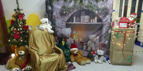 Powiększ grafikę: Przystrojony kącik - widać choinkę, fotel świętego Mikołaja, skrzynkę na listy, tło z kominkiem, kilka pluszowych misiów.