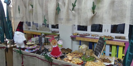 Powiększ grafikę: Stoisko ze słodkościami udekorowane gałązkami i ozdobami świątecznymi.