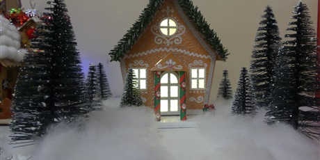 Powiększ grafikę: Praca plastyczna - domek wykonany z tektury. W środku włączone światełka. Przed domkiem wata, choinki.