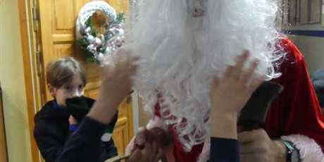 Powiększ grafikę: Dziecko łapie za brodę świętego Mikołaja.