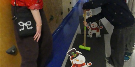 Powiększ grafikę: Dziewczynka trzyma w dłoni kij - przebija piłkę przez dziurę w tekturowych bałwankach.