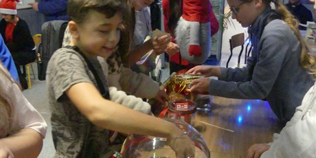 Powiększ grafikę: Chłopiec trzyma dłoń w szklanej kuli - losuje karteczkę.