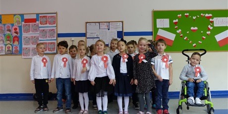 Powiększ grafikę: Grupa dzieci z biało-czerwonymi kotylionami, występują przed innymi.