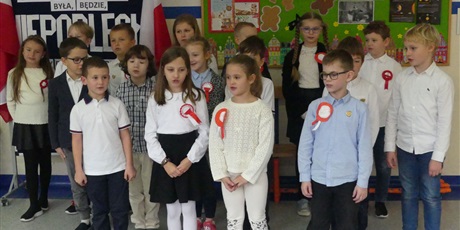 Powiększ grafikę: Grupa dzieci występuje na środku korytarza - śpiewają piosenkę.