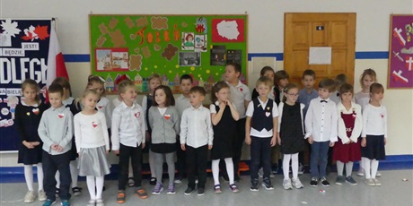 Powiększ grafikę: Grupa dzieci stoi na środku korytarza, występują.