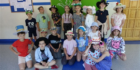 Powiększ grafikę: Grupa dzieci na korytarzu szkolnym - na głowach mają kolorowe, ozdobione kapelusze.
