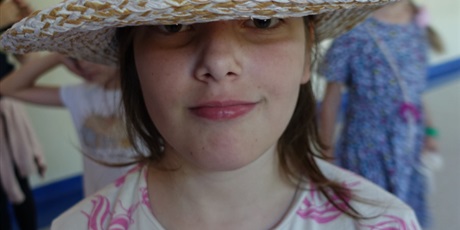 Powiększ grafikę: Dziewczynka z ozdobionym kolorowymi pomponami kapeluszu na głowie.