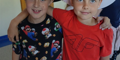 Powiększ grafikę: Dwóch chłopców, przytulają się. Na głowach mają ozdobione kapelusze.
