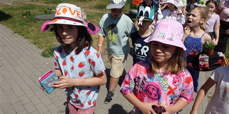 Powiększ grafikę: Grupa dzieci kolorowo ubranych, na głowach mają ozdobione kapelusze, śmieszne nakrycia głowy.