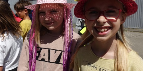 Powiększ grafikę: Dwie uśmiechnięte dziewczynki z kolorowymi kapeluszami na głowach.