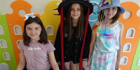 Powiększ grafikę: Trzy dziewczynki na korytarzu szkolnym - mają ozdobione kapelusze na głowach.