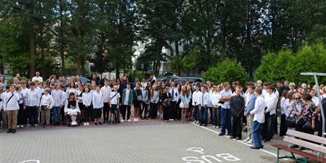 Powiększ grafikę: Grupa uczniów na rozpoczęciu roku szkolnego, stoją na placu przed szkołą.